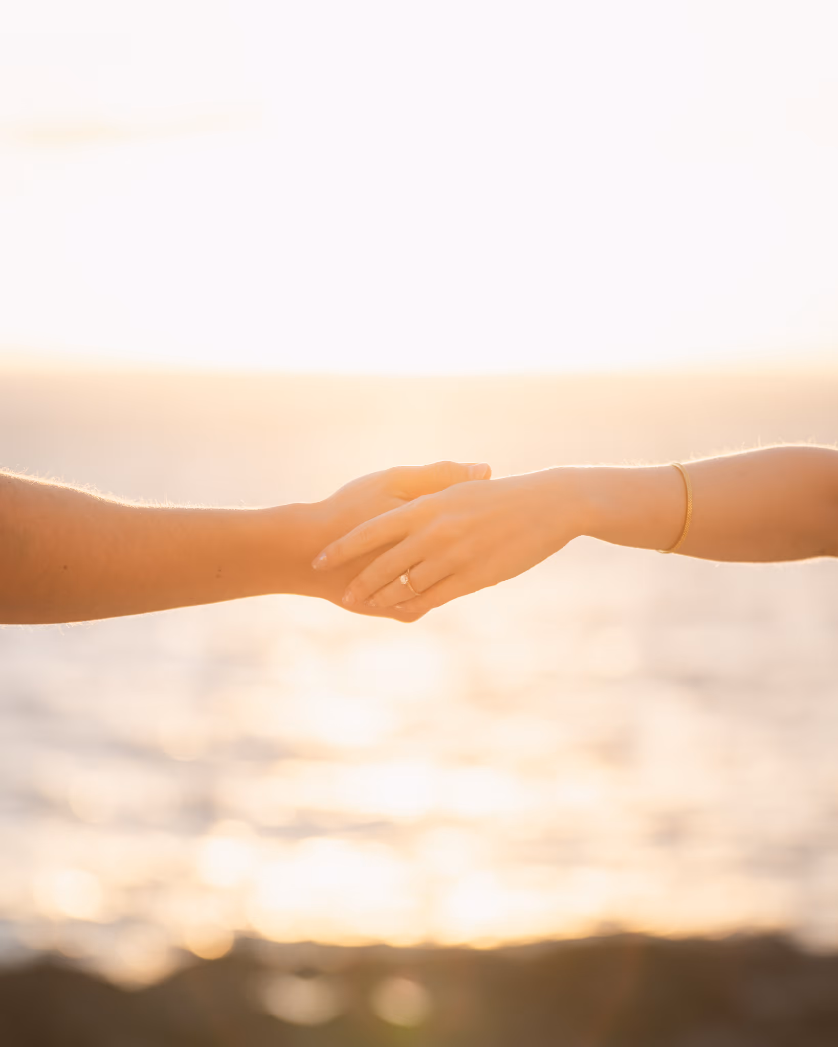 Manos de una pareja unidas al atardecer en una playa de Tenerife, con el anillo de compromiso